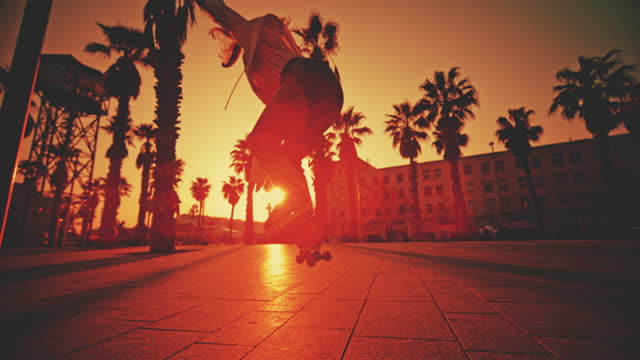 SUPER SLOW MOTION TIME WARP of female skater roller skating on footpath at town square. Back lit young woman is practicing stunt. She is in city during sunset.