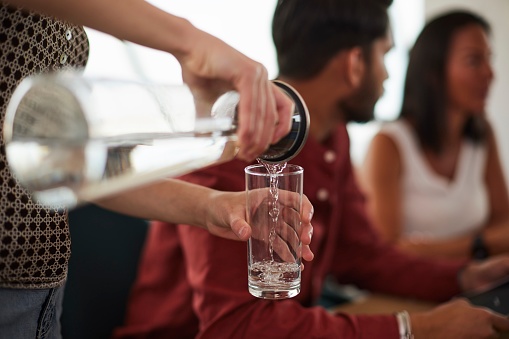 Close-Up View of Hands Pouring Water into an Attendee's Glass