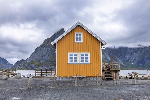 A yellow fishing cabin in Sakrisøy, a small fishing village on Lofoten islands, Norway with a mountain in background