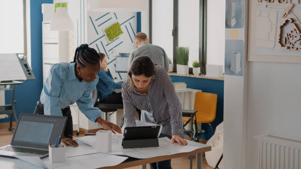 istock Team of architects working with blueprints plans and tablet to design building structure 1491313022