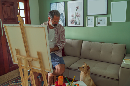 An elderly man painting in the cozy ambient of his home