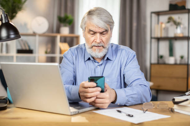 istock Business leader using phone at desk with laptop in workplace 1491313562