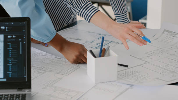 istock Close up of architects doing teamwork to design blueprints plans for building model on table 1491313777