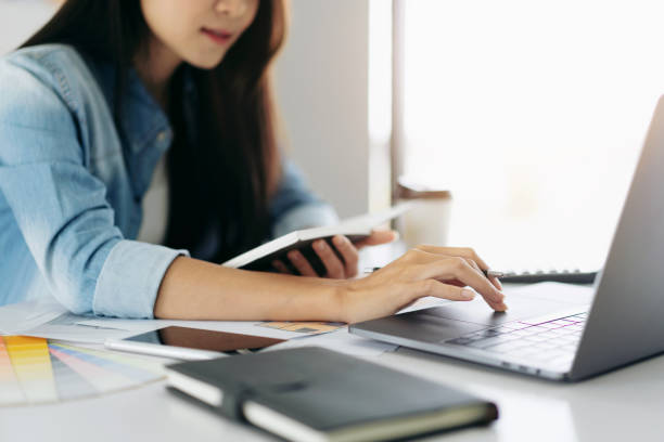 istock Woman architect holding notebook and typing data on laptop to sk 1491315215