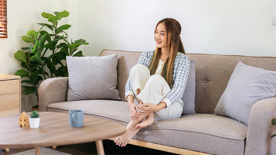 Woman enjoying dreamy and relaxing with looking outside while sitting on the comfortable sofa to leisure with cozy lifestyle in living room at home.