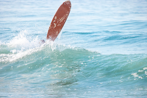 Noordhoek Beach at sunset. Surfing in Cape Town, South Africa. Surfer tries to take a high and powerful wave. Atlantic coast in Table Mountain National Park. Extreme sports leisure concept.