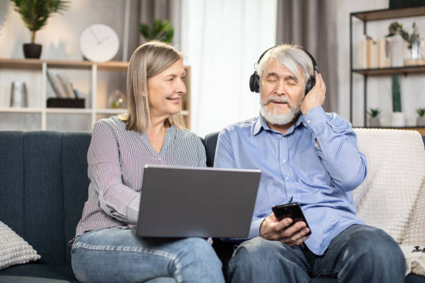 istock Funny senior pair having fun using laptop and headphones 1491316893