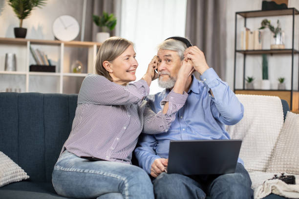 istock Funny senior pair having fun using laptop and headphones 1491316901
