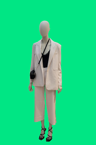 Full length image of a female display mannequin wearing fashionable white trouser suit isolated on a green background