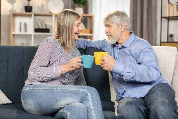 istock Senior couple drinking tea on sofa in cozy living room 1491318708