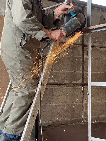 worker while cutting an iron structure with a grindstone