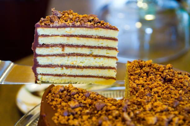 istock Six layer white cake with chocolate frosting and nuts on top with a large piece cut out for display 1491320182