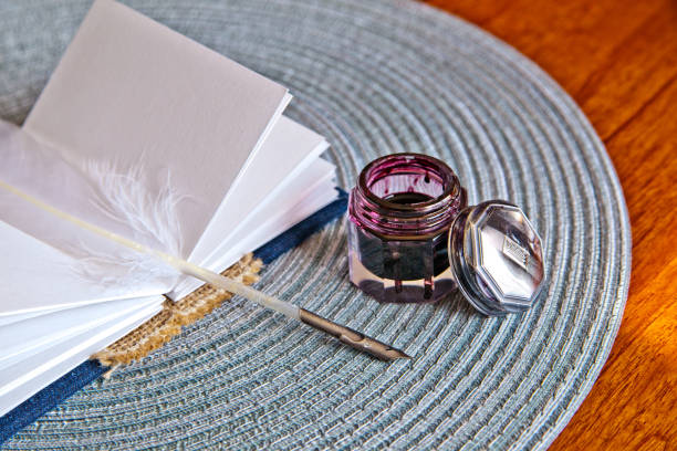 istock Small journal book and white feather quill lay on a placemat next to an open ink pot 1491320541