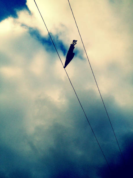 The dangling sneakers create a striking silhouette against the gray backdrop of an overcast day