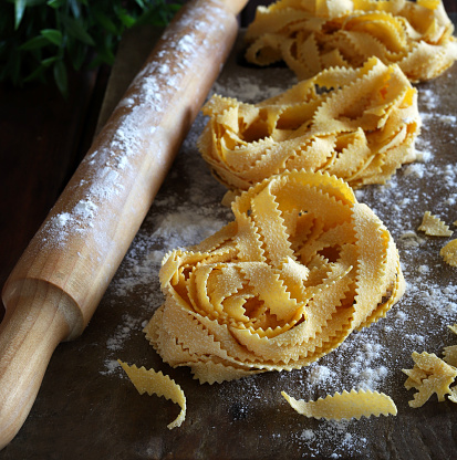 Italian cuisine. Homemade pasta pappardelle and rolling pin isolated on rustic wooden background. Overhead view.