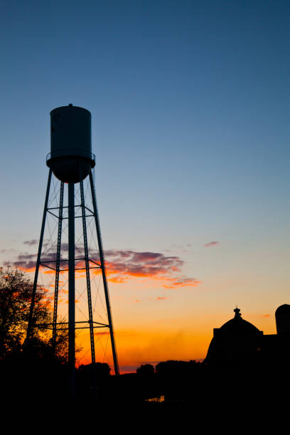 istock Water tower and barn silhouetted against the setting sunlight 1491324469