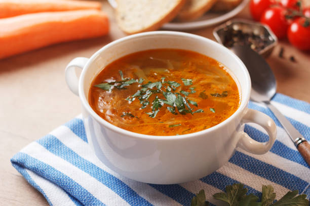 istock Vegetable soup with potatoes, cabbage, carrots and onions in a white bowl on the kitchen table. Vegetarian food. 1491324986