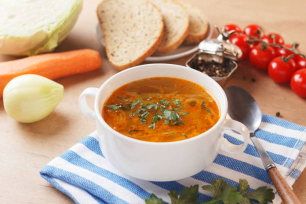 istock Vegetable soup with potatoes, cabbage, carrots and onions in a white bowl on the kitchen table with cereal bread. Vegetarian food. 1491325002