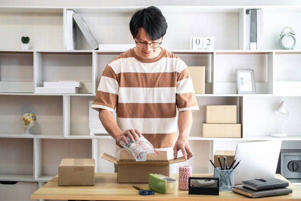 istock Male entrepreneur is packing the product into cardboard boxes fo 1491325675