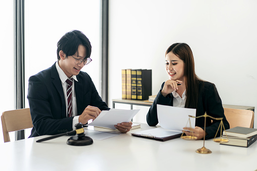 Female lawyer is discussing and legal advice about business contract to client while businessman holding to pointing on document and asking about laws and agreements of contracts in law firm office.