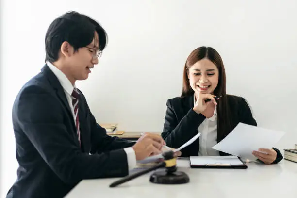 Female lawyer is discussing and legal advice about business contract to client while businessman holding to pointing on document and asking about laws and agreements of contracts in law firm office.