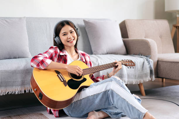 istock Young woman is playing guitar and singing the song while wearing 1491325773