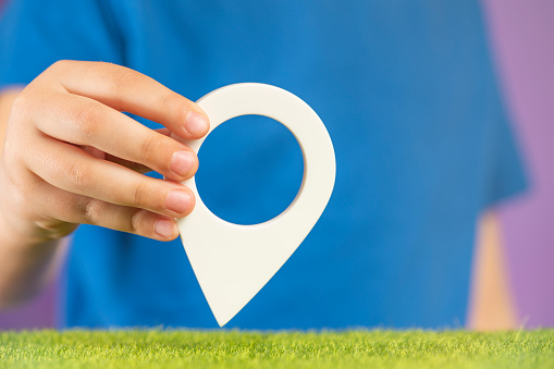 Travel concept. Hand holding pin icon or navigation tag. GPS direction indicator. Location sign in hands. Route laying. High quality photo