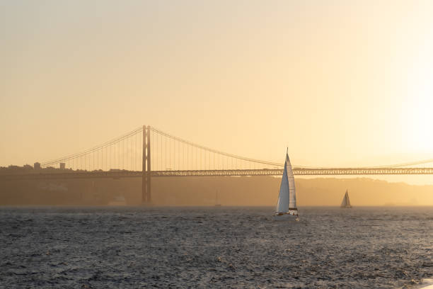 해질녘 리스본 항구로 향하는 레저 세일링 요트 - sailboat pier bridge storm 뉴스 사진 이미지