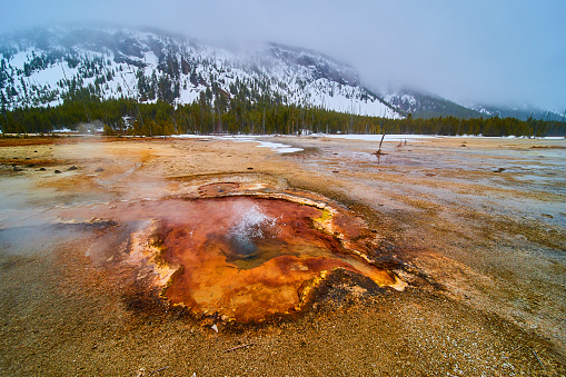 Image of Yellowstone in winter with acidic colorful pools and steam