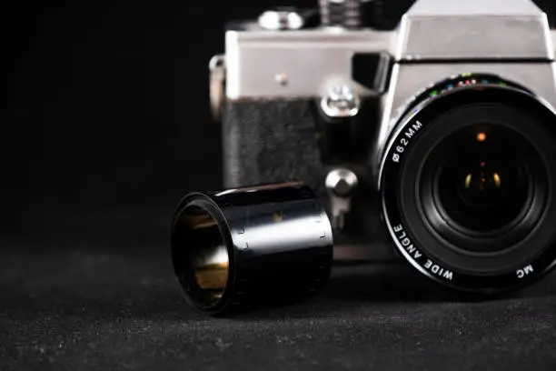 Detail photo of a metal-bodied analog camera and 35mm film taken in a light box with studio light effect