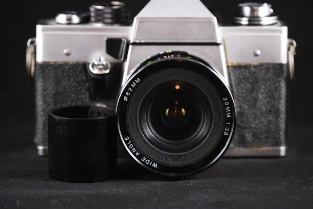 Detail photo of a metal-bodied analog camera and 35mm film taken in a light box with studio light effect