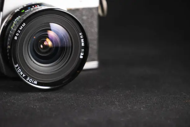 Detail photo of a metal-bodied analog camera and 35mm film taken in a light box with studio light effect