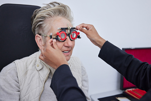 Eye exam, frame and senior woman with optometrist in clinic for vision, eyesight and optical assessment. Ophthalmology, healthcare and optician with trial glasses, optometry and medical tool for eyes