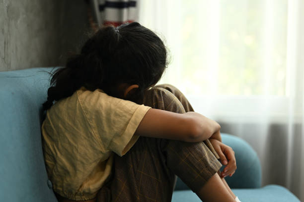 Lonely sad girl student crying and hug her knees sitting in corner Lonely sad girl student crying and hug her knees sitting in corner, Sad and unhappy child portrait, Sad child sitting on sofa at home, Concept of lonely girl and kid with trouble and violence child sadness stock pictures, royalty-free photos & images