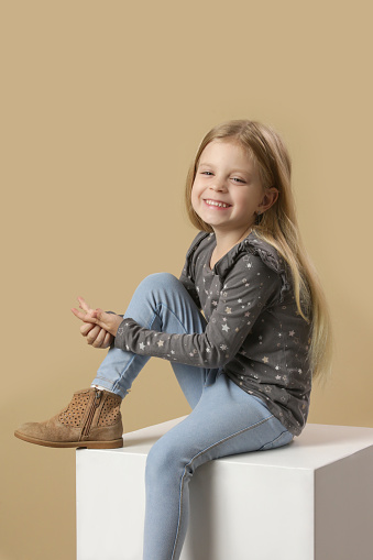 Studio portrait of adorable little girl on beige background