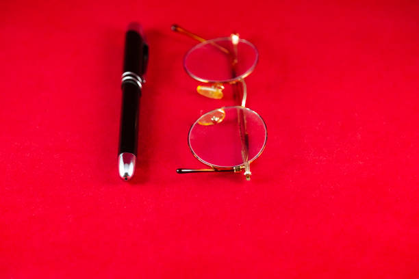 Glasses, Pen, and Magnifying Glass on Orange Surface with Yellow Circles