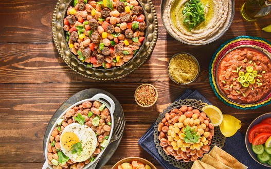 Arabic Cuisine: Varieties of traditional Egyptian beans dishes consisting of beans with sausage,  tahini ,eggs, chickpeas, olive oil and also with spicy tomato sauce. Top view with close up.