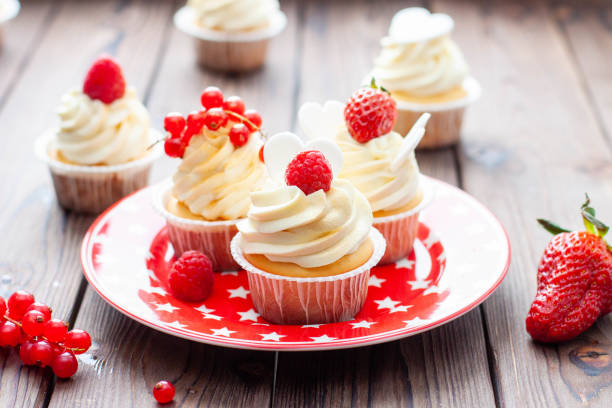 istock Vanilla cupcakes decorated with fresh strawberry, raspberry and red currant on rustic wooden background 1491332480