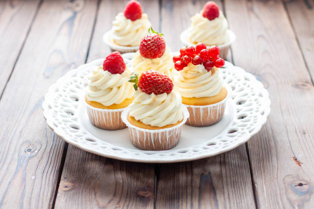 istock Vanilla cupcakes decorated with fresh strawberry, raspberry and red currant on rustic wooden background 1491332481