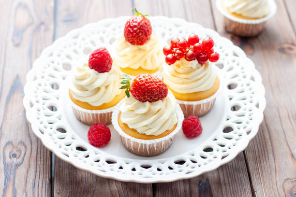istock Vanilla cupcakes decorated with fresh strawberry, raspberry and red currant on rustic wooden background 1491332484
