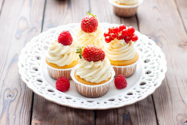 istock Vanilla cupcakes decorated with fresh strawberry, raspberry and red currant on rustic wooden background 1491332485