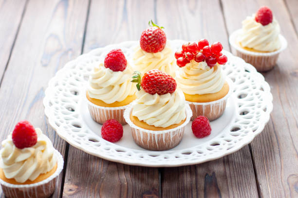 istock Vanilla cupcakes decorated with fresh strawberry, raspberry and red currant on rustic wooden background 1491332486