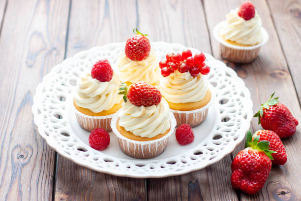 istock Vanilla cupcakes decorated with fresh strawberry, raspberry and red currant on rustic wooden background 1491332487