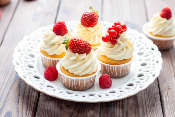 istock Vanilla cupcakes decorated with fresh strawberry, raspberry and red currant on rustic wooden background 1491332492