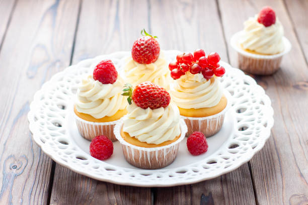 istock Vanilla cupcakes decorated with fresh strawberry, raspberry and red currant on rustic wooden background 1491332500