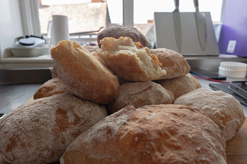 A pile of freshly baked ciabatta white crusty home-made rolls on a rustic wooden table, Top view, Side view.