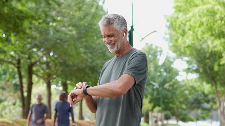 Senior man runner looking at smartwatch outdoor activity