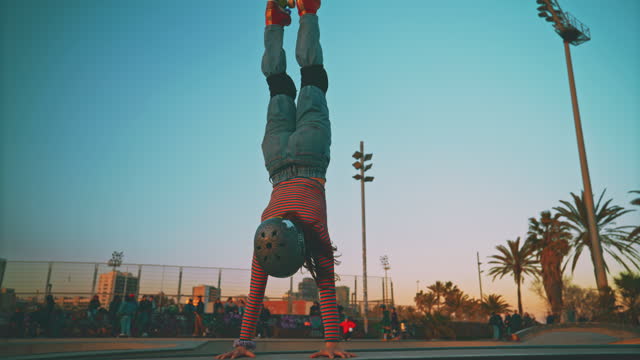 SLO MO Young female roller skater performs acrobatic move - handstand in the skate park
