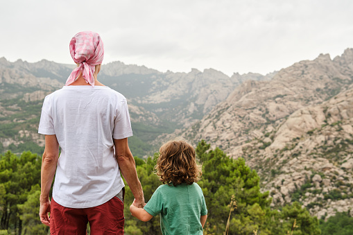Woman with pink scarf against breast cancer in nature with her son
