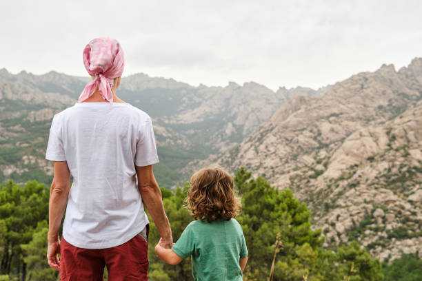 A Woman with pink scarf against breast cancer in nature with her son stock photo